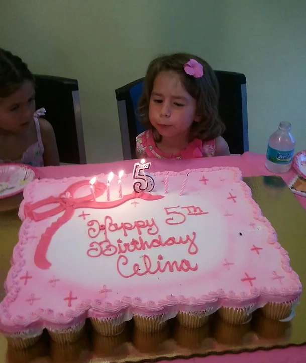 girl blowing out candles on cake